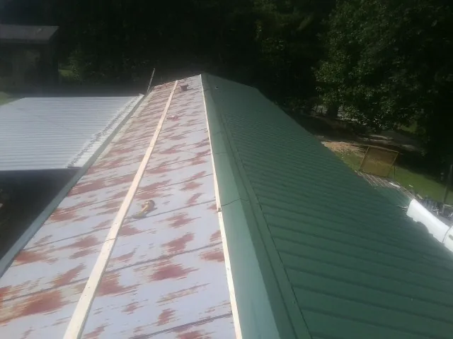 Old rusted panels beside newly installed green metal roofing — Wind Damage Roof Repair by Roofing Brothers in Lucama