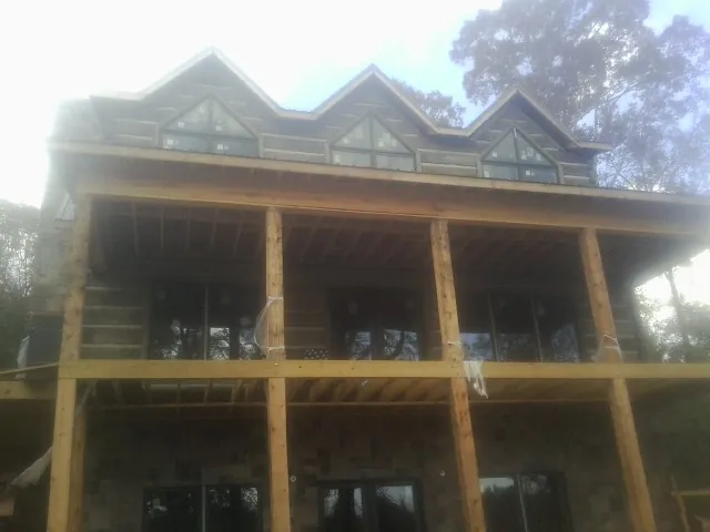 Dormers and porch framing on a large log home under construction — Roof Coating work by our crew in Lucama