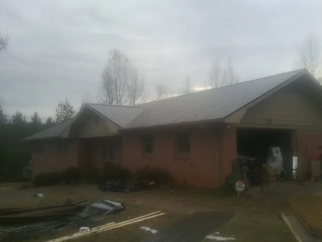 Gray metal roof on a stucco house with an attached garage in Lucama