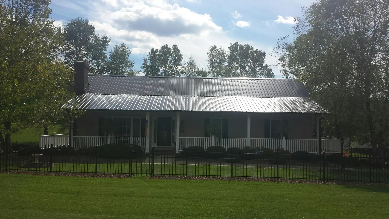 Gray metal roof on a brick ranch with a full width front porch — Gutter Guard Installation work by our crew in Lucama